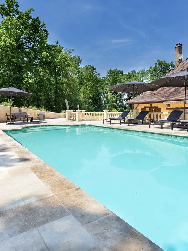 Heated pool, large terraces with lounging chairs surrounded by a forest Heated pool, large terraces with lounging chairs surrounded by a forest